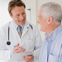 Doctor chatting with a senior patient in an exam room.