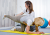 Image of a physical therapist helping a patient perform a trunk exercise for spine fusion rehabilitation