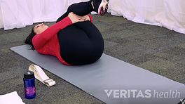 Woman performing single knee to chest exercise.