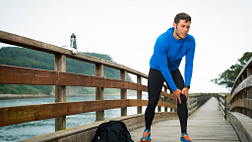 Image of a man in workout clothes holding his knee in pain