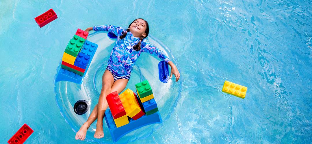 LEGOLAND Florida piscina Imagem aérea de uma menina em uma grande boia na piscina, cercada por Legos.”