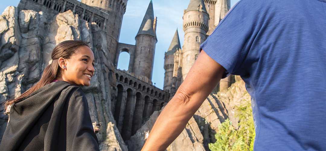 Hogwarts™ castle in Hogsmeade at Universal's Islands of Adventure Mother and daughter, smiling, holding hands, and walking to Hogwarts™ castle in Hogsmeade at Universal's Islands of Adventure.
