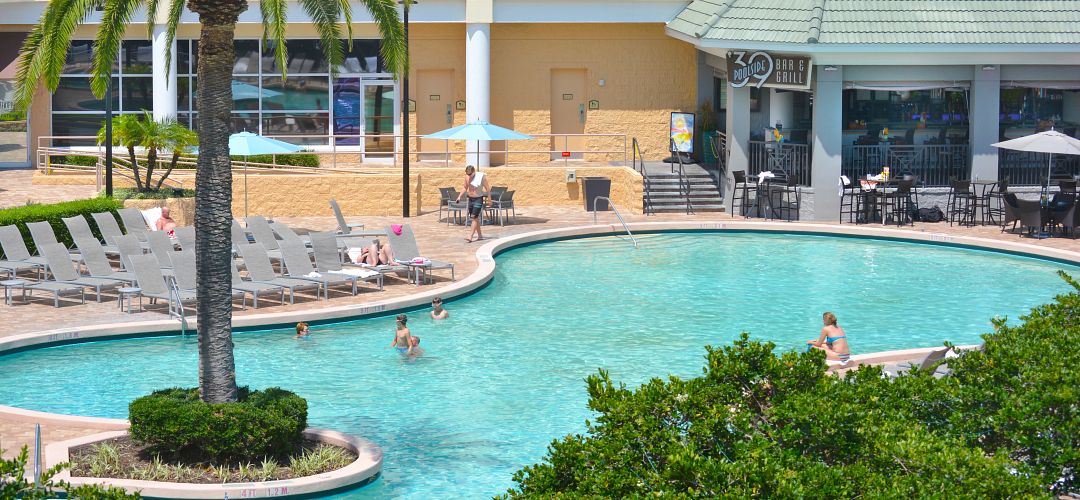Rosen Plaza in Orlando Exterior aerial shot of the pool at Rosen Plaza. Children playing inside the pool and adults lounging nearby on a sunny day in Orlando.
