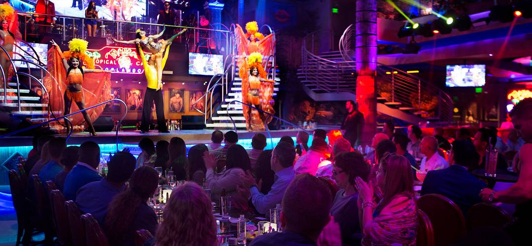 Mango's Tropical Café Grupo de personas cenando y presenciando un espectáculo de baile dentro del establecimiento Mango's Tropical Cafe