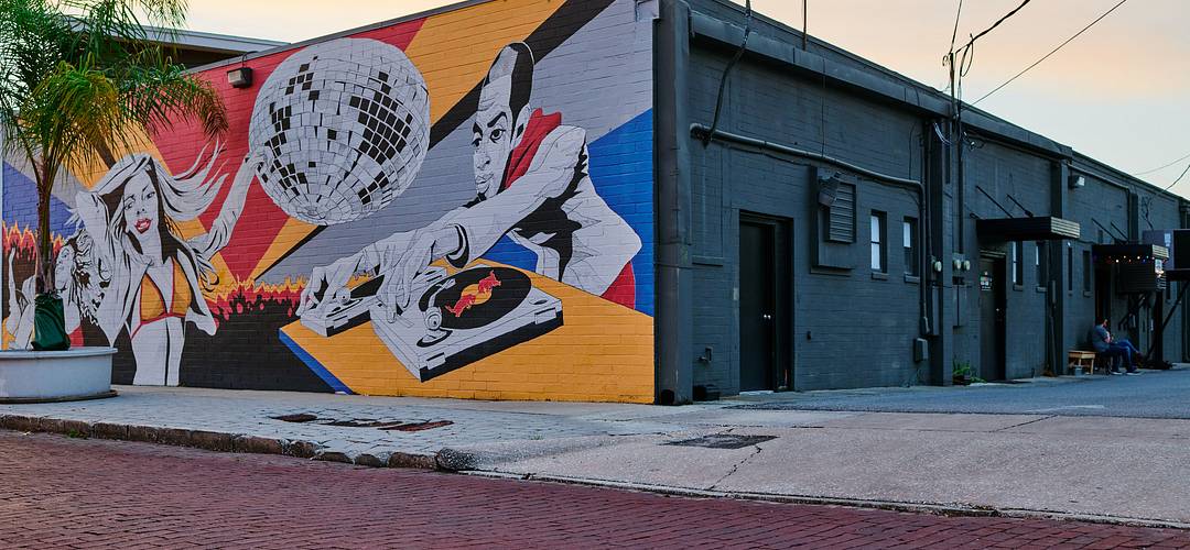 Mills 50 Mural Colorful mural of a DJ playing music with people dancing on a building wall at Mills 50