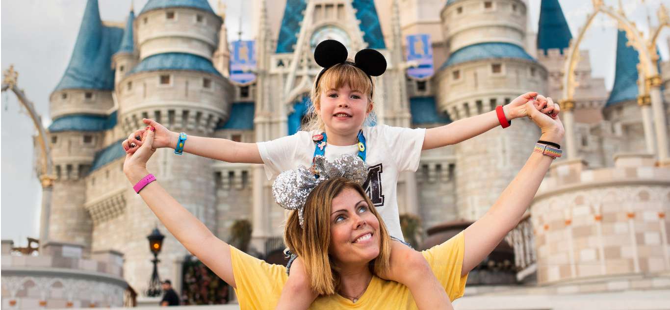 Disney’s Magic Kingdom A mother lifts her child with Cinderella’s Castle in the background.