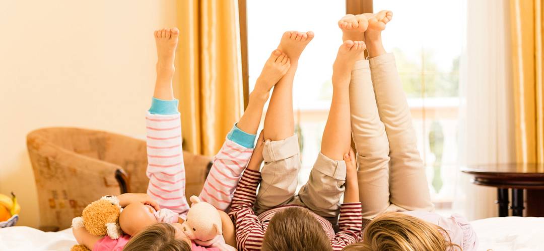 Unique Family Suites Children lying down on a bed with legs in the air