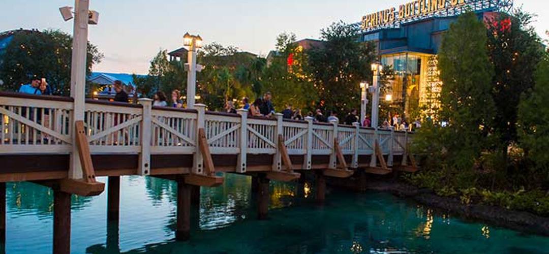 Disney Springs Pedestrians cross a footbridge during twilight at Disney Springs