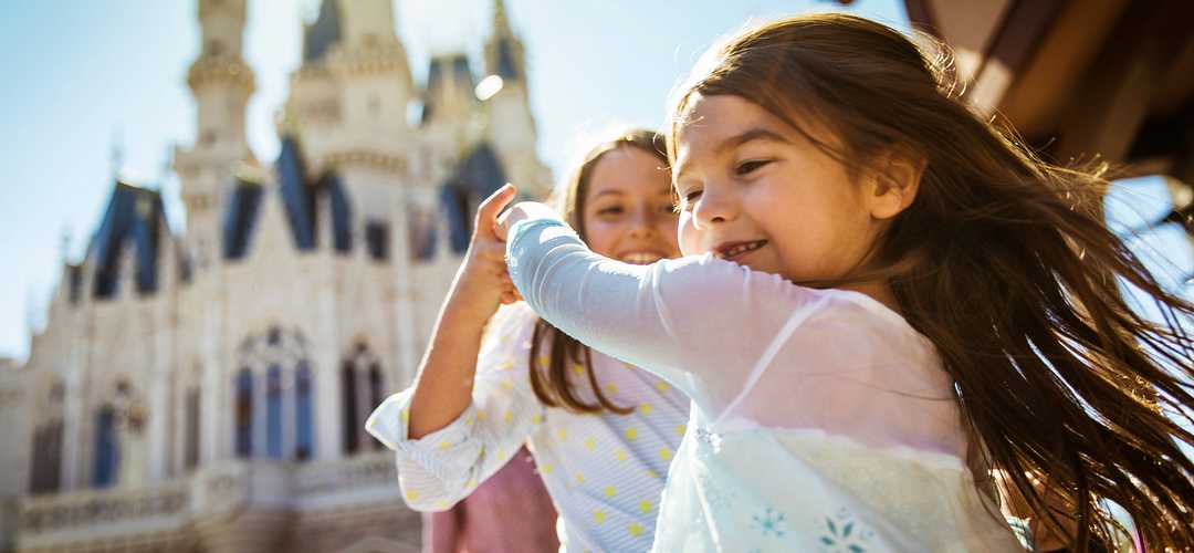 Dancing at Disney’s Magic Kingdom Young sisters twirl and dance in the sunlight with Cinderella’s Castle in the background.