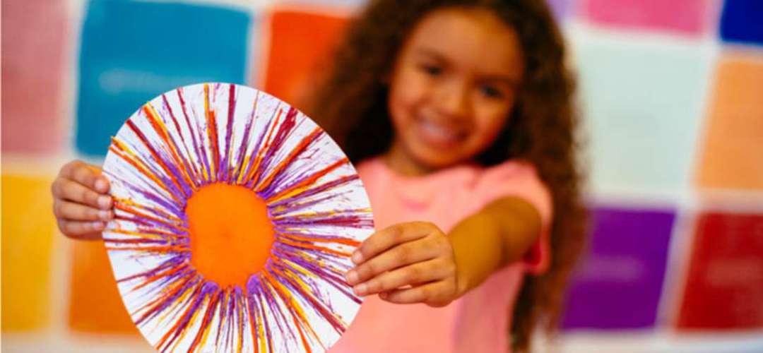 Crayola Experience A girl proudly holding drip art created at Crayola Experience