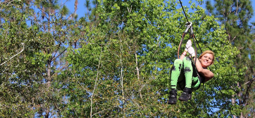 Orlando Tree Trek Adventure Park woman riding a zipline throuh a forest