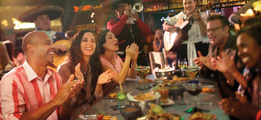 Food, family, and friends; where to eat at Universal Studios Florida A mariachi group playing while friends sing and clap with food and drinks at the table at Antojitos.