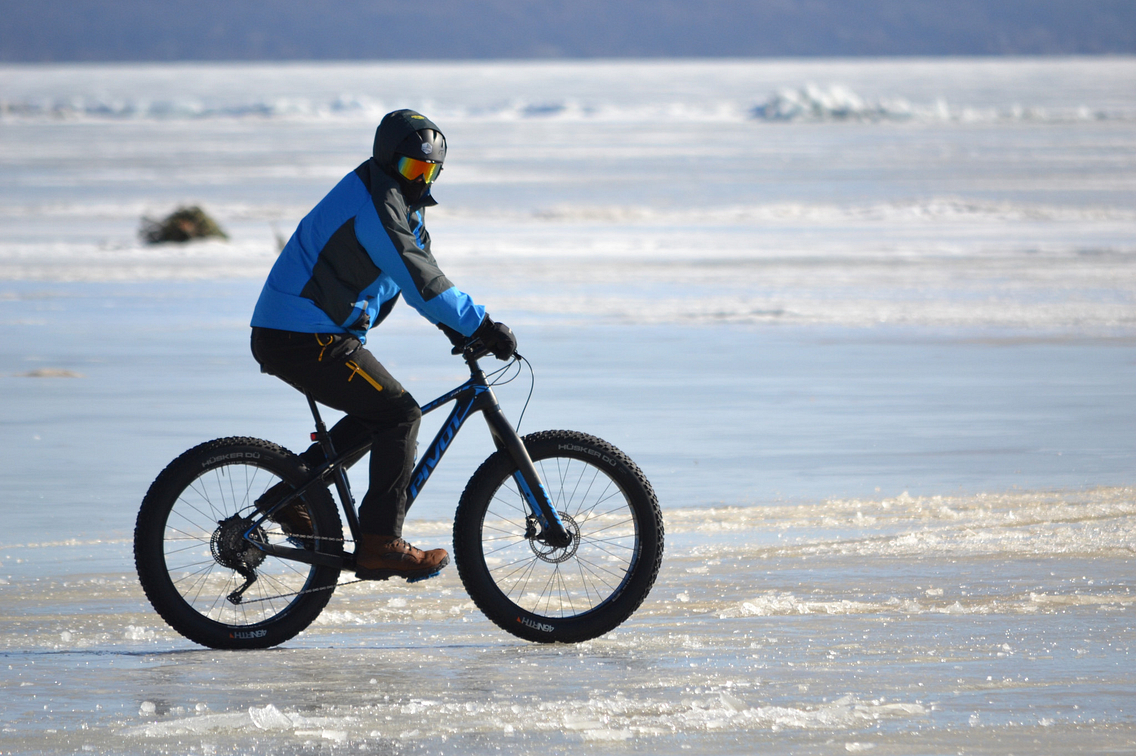 Bundled-up rider on fat-tire bike crossing frozen lake