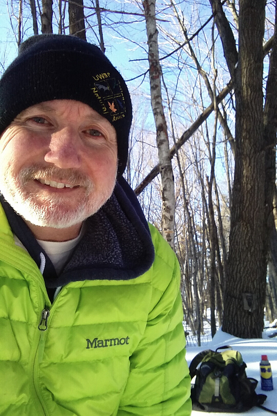 Closeup of man in neon green winter jacket in wintry, wooded setting