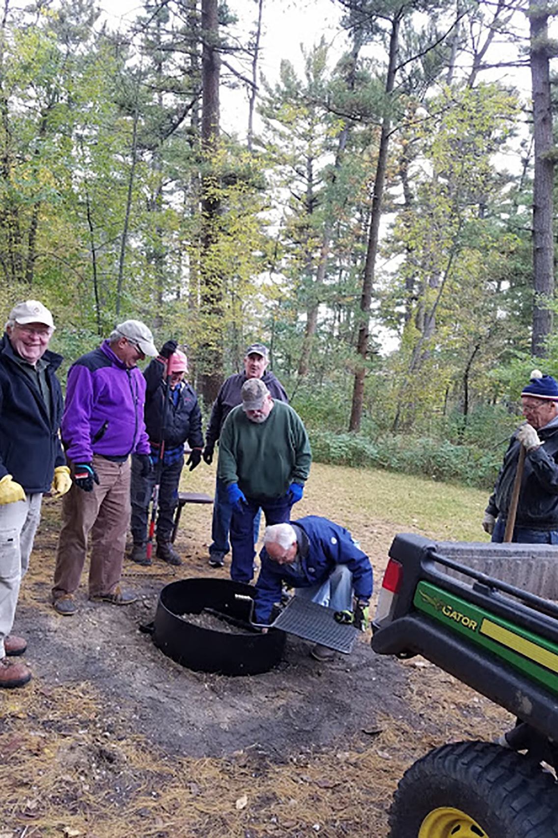 Group of men helping install a fire ring at Kohler-Andrae State Park