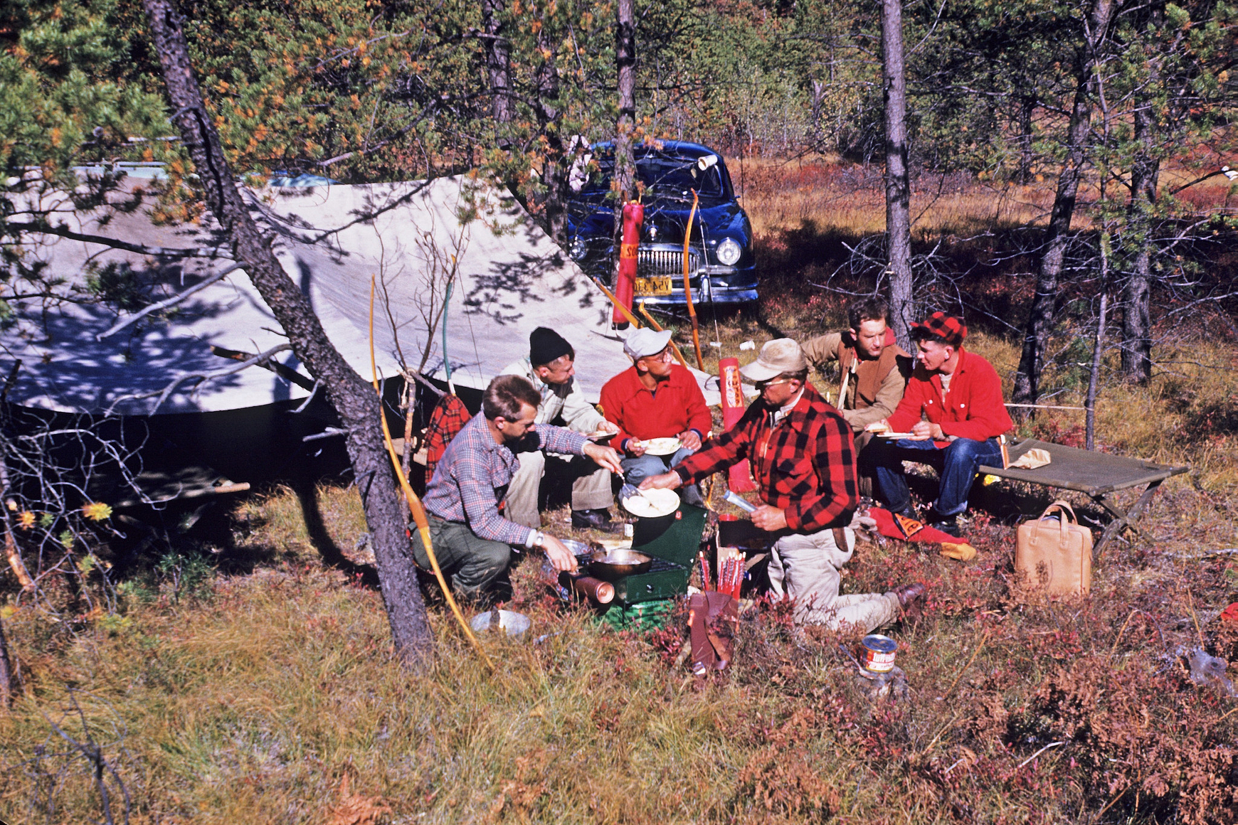 Vintage color photo of group of hunters sitting at campsite and preparing meal