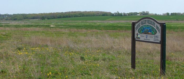 a photo of the entrance sign to Turtle Valley Wildlife Area with the land showing behind it.