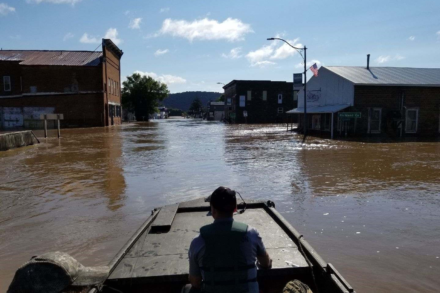 Photo of DNR warden in boat in flooded street in Viola.