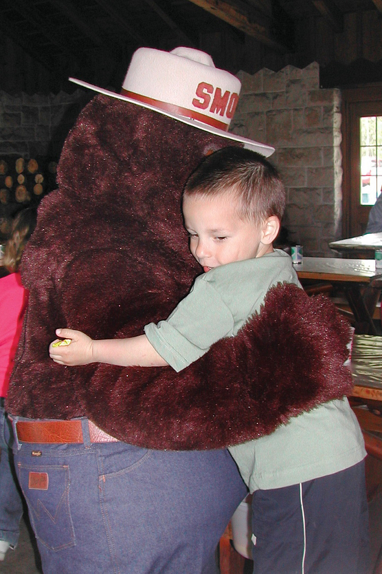 Photo of Smokey Bear hugging a young boy