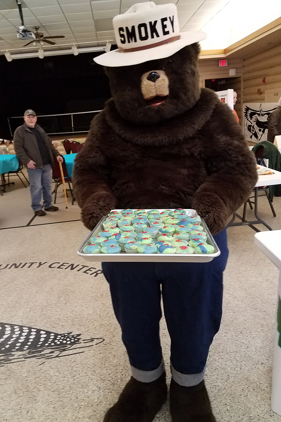 Photo of Smokey Bear holding tray of cupcakes