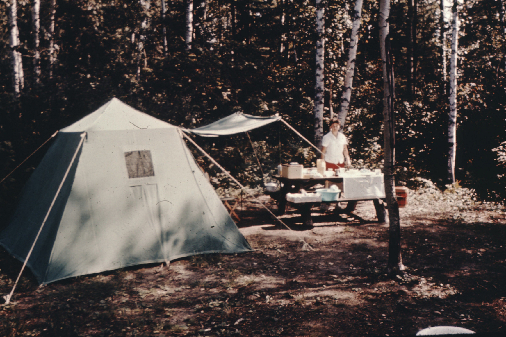 Woman standing next to picnic table at campsite