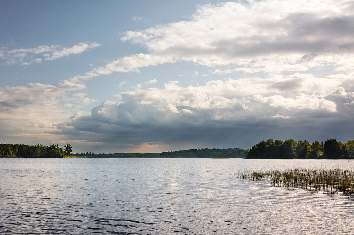 Sun setting over a lake with storm clouds gathering