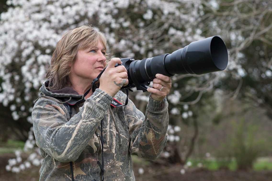 Woman in forest with long-lensed camera