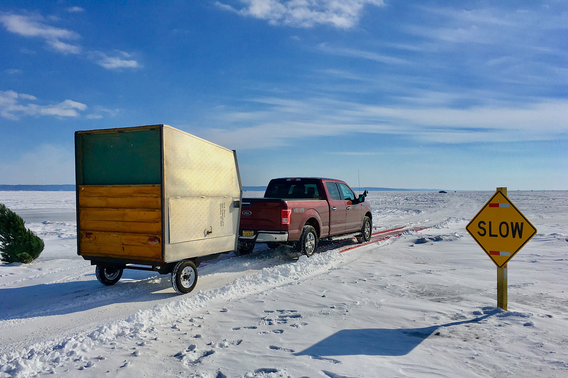 Truck pulling ice shanty across frozen lake