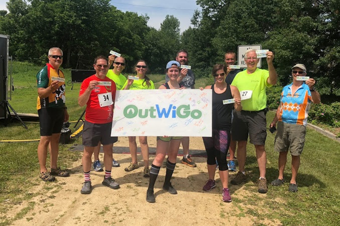 Group of people in outdoor gear with OutWiGo sign