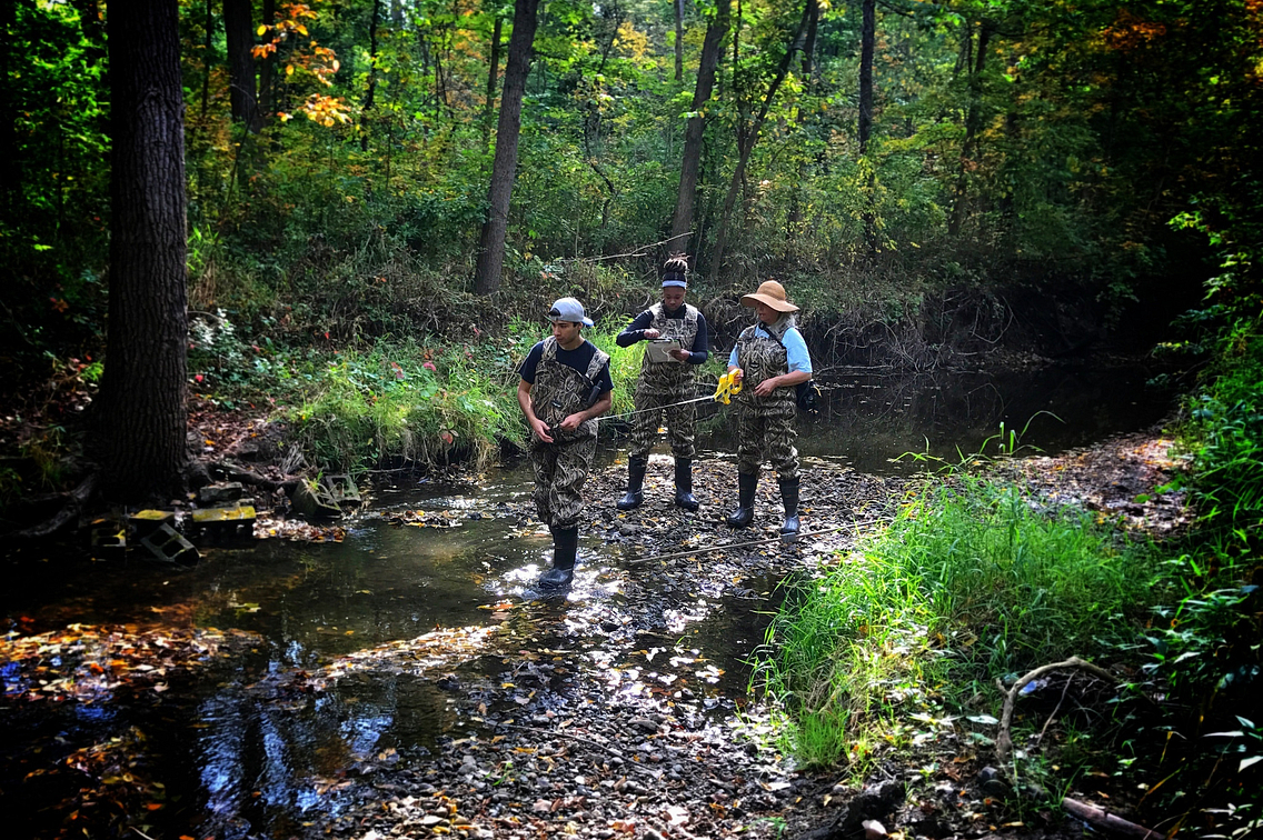 Photo of group of young people with boots on standing in a stream