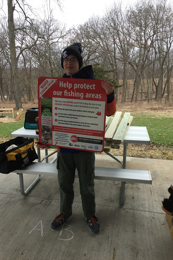 Young boy in green stocking hat holding a sign about protecting fishing areas