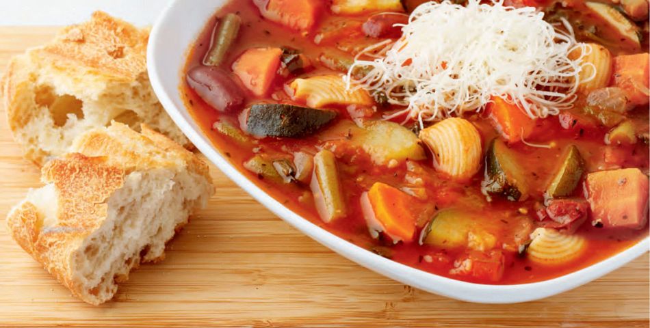 minestroni soup on table with bread and spoon
