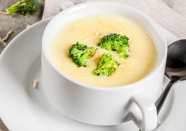 Broccoli Chedder Soup Served in a cup with pieces of broccoli on top