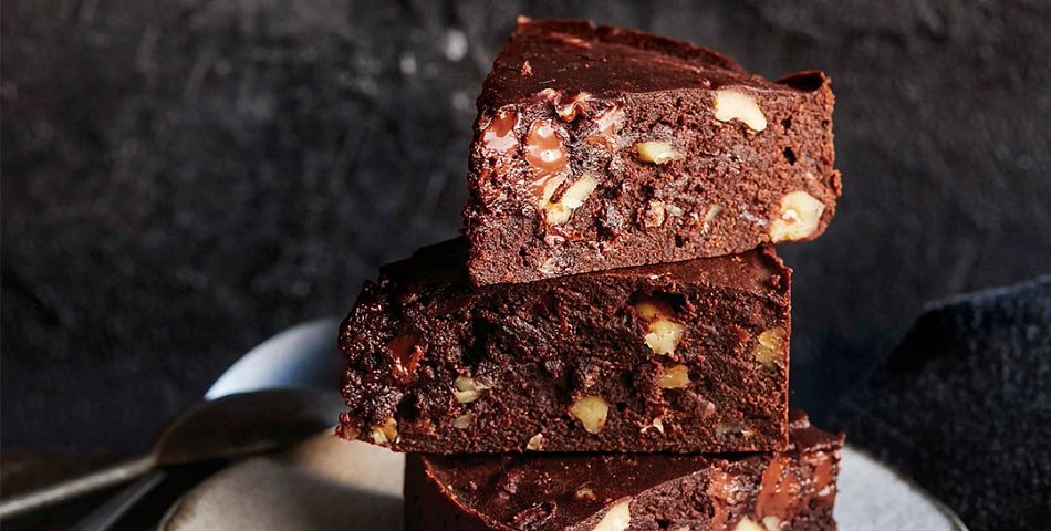Fudge Brownie Cake with Toasted Walnuts stacked 3 high on a plate