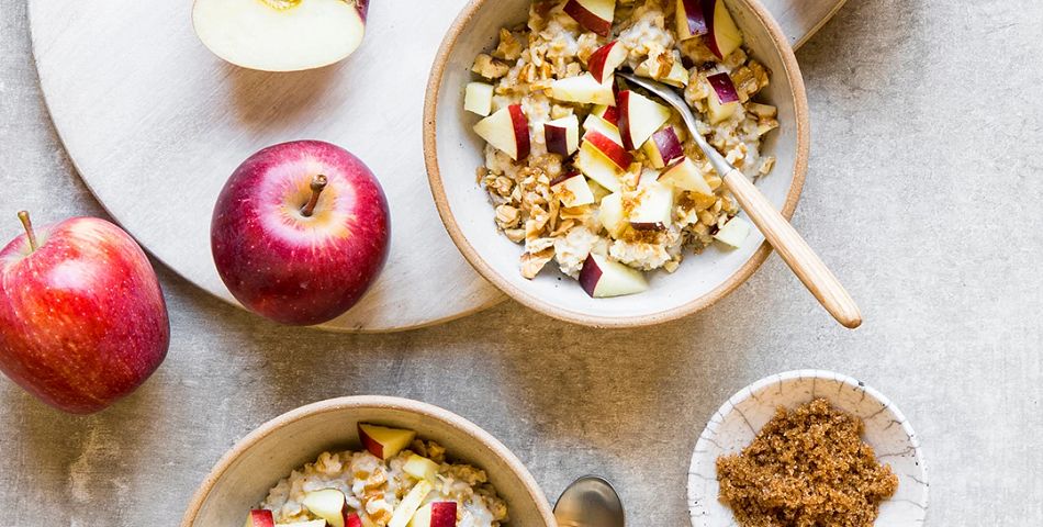 Apple Cinnamon Oat Porridge in bowls on the table with cinnamon and apples on the side