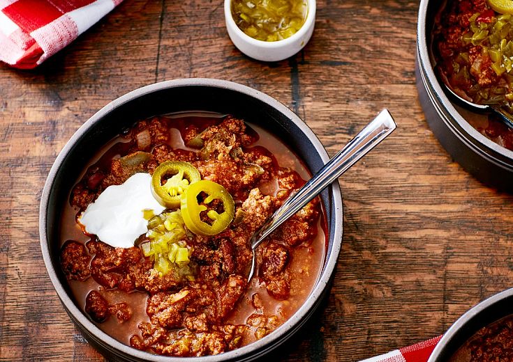 Firehouse Chili in a pot with jalepenos on top on the table